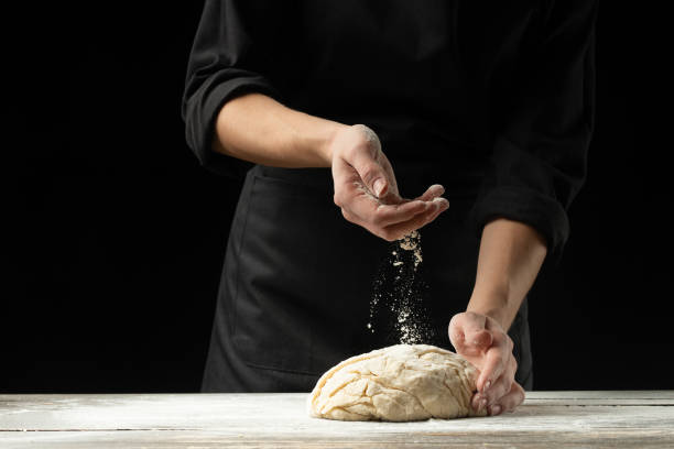 istock Bakery. Man preparing the bread, Easter cake, Easter bread or cross buns on a wooden table in the bakery close up. Cook preparing bread dough. 1079859036