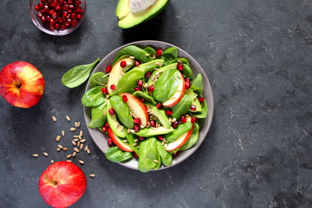 istock Fresh salad with spinach, avocado, apple, pomegranate and sunflower seed critters on dark background. 1079861366
