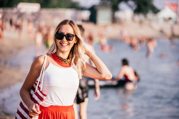 istock Smiling young woman with bag on the beach 1079881014