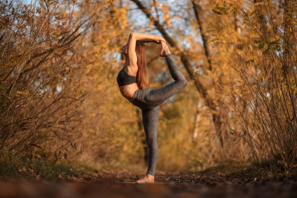 istock Young woman practicing yoga exercise at autumn park with yellow 1079897094