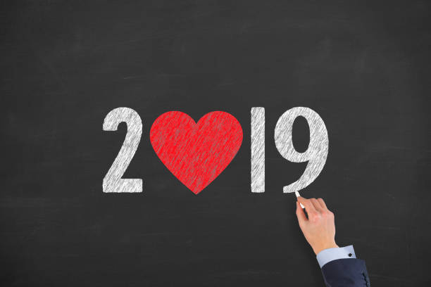istock Human Hand Drawing New Year 2019 with Heart Shape on Chalkboard Background 1079914156
