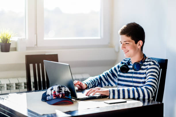 istock Teenage boy using laptop while relaxing at home 1079914566