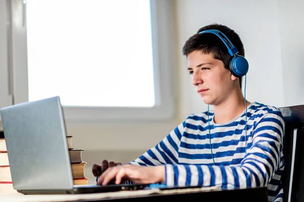 istock Teenage boy using laptop while relaxing at home 1079917838