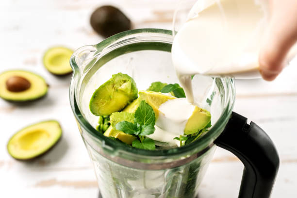 Top view of blender with avocado peaces Pouring vegetarian cream into blender with avocados. Healthy ice cream preparation blender photos stock pictures, royalty-free photos & images