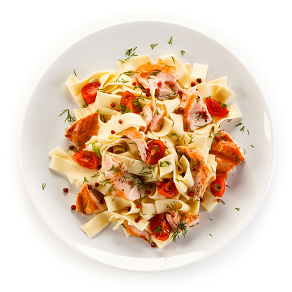 Pasta with salmon and vegetables on white background