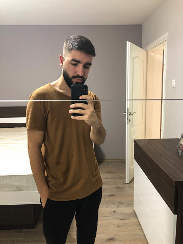 Man taking selfie in front of mirror at home