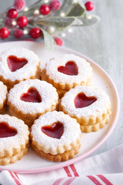 traditionelle weihnachten linzer cookies gefüllt mit erdbeer-marmelade auf leuchttisch mit weihnachts-dekorationen - cookie heart shape shortbread christmas stock-fotos und bilder