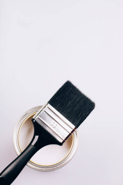 istock Brush with black handle on open can of white paint on grey background. 1079938944