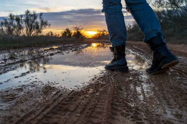 Photo of Walking through a puddle with military boots with the sunset reflected.