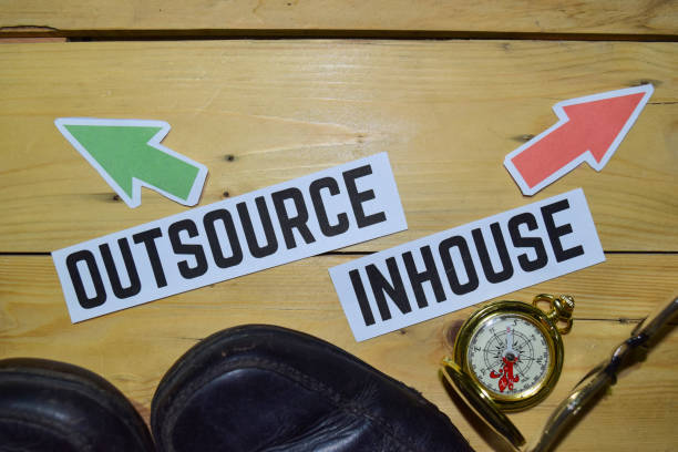 Outsource or Inhouse opposite direction signs with boots,eyeglasses and compass on wooden vintage background.