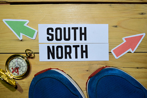 South or North opposite direction signs with sneakers and compass on wooden vintage background.