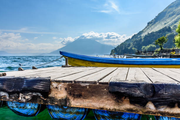 Boat docked at jetty with San Pedro volcano behind on Lake Atitlan, Guatemala.