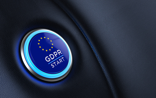 Car start button textured with European Union flag on dashboard. GDPR Start writes on push button. Horizontal composition with copy space and selective focus.