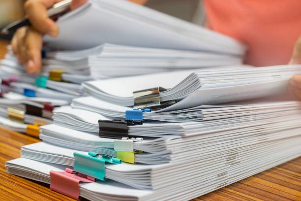 istock Teacher hand holds pen for checking student's homework assignment on table office. Paper documents stacked in archive with paperclip. Report papers stacks. Business and education concept. 1080067938