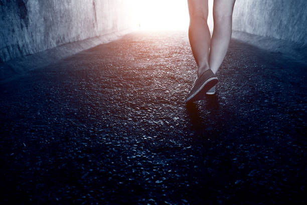 Woman walking through a dark tunnel.