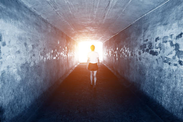 istock Woman walking through a dark tunnel 1080116382