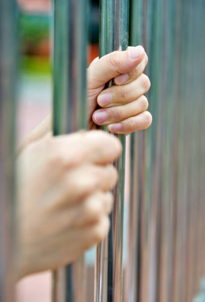 Woman hand gripping the jail bars.