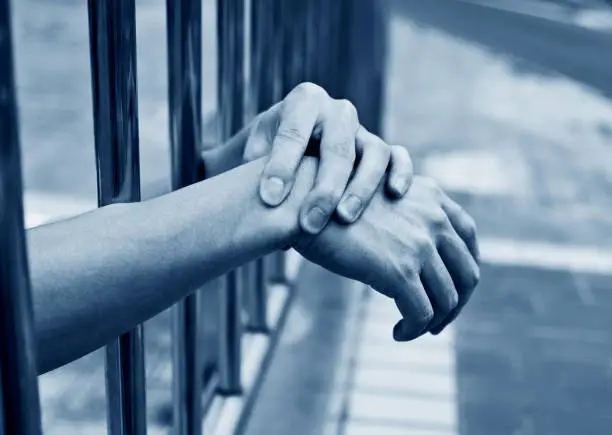 Photo of Man hand on the jail bars