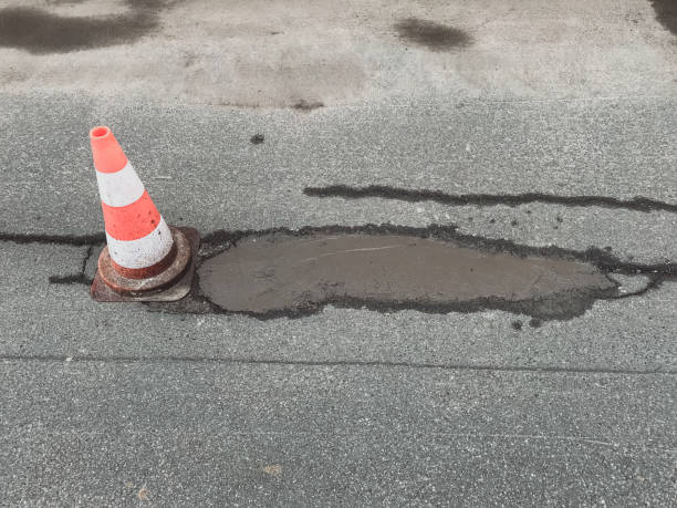 istock Patched pothole on a small rural road with a warning sign 1080125470