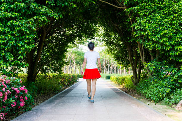 donna che cammina attraverso il tunnel naturale verde - women rear view one person arch foto e immagini stock