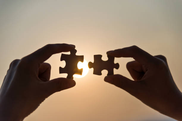 istock Woman hand putting puzzle pieces together in sunset 1080129772
