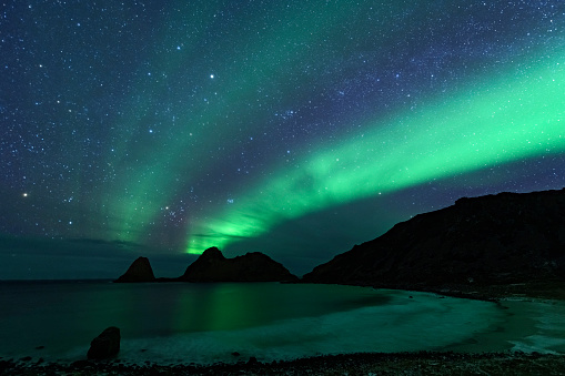 Norhtern Lights or aurora  over the snowy mountains in Northern Norway during a cold winter night.