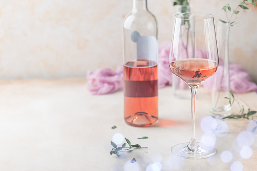 Glass and bottle of rose wine on light background.