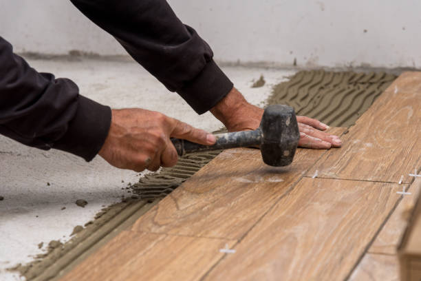 istock Worker placing ceramic floor tiles on adhesive surface, leveling with rubber hammer. 1080145444