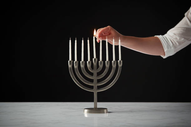 黒スタジオ背景に大理石の表面に金属のハヌカ本枝の燭台に手照明キャンドル - hanukkah menorah human hand lighting equipment ストックフォトと画像