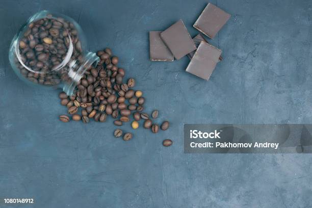 Roasted Coffee Beans Poured From A Glass Jar Angular Placement Of A Coffee Object With Chocolate Pieces On Dark Concrete View From Above Copy Space Stock Photo - Download Image Now