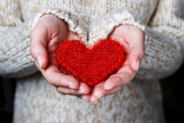 la ragazza con un maglione leggero dona un cuore a maglia. - religious images immagine foto e immagini stock