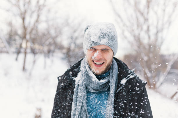 istock Surprised man feeling cold snowflakes on his face during a snow 1080154064