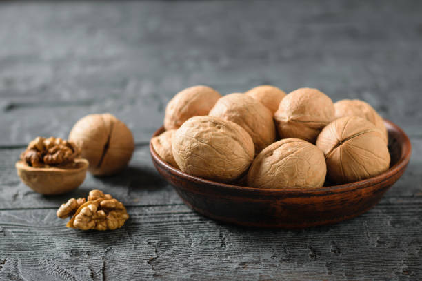 istock Split walnut with a clay bowl full of nuts on a dark rustic table. 1080163336