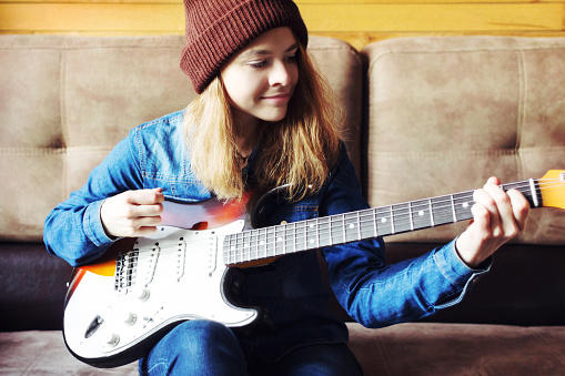 Teenager playing guitar at home.