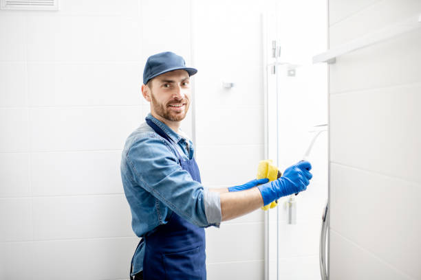 Man cleaning bathroom Man as professional cleaner wiping the shower door with cotton wiper in the white bathroom custodian stock pictures, royalty-free photos & images