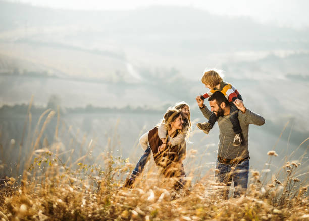 padres sin preocupaciones que se divierten con sus hijos en un campo. - outdoors offspring women fall fotografías e imágenes de stock