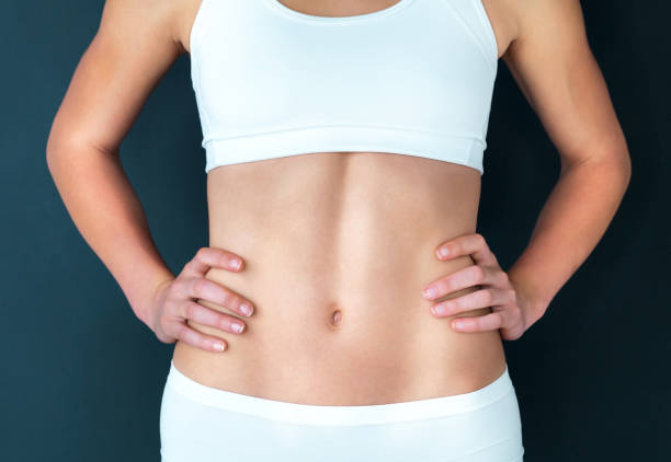 Healthy starts with the stomach Studio shot of a fit young woman standing with her hands on her hips against a dark background stomach stock pictures, royalty-free photos & images