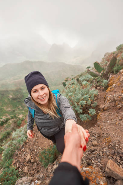 let me help you hikers helping each other in spring day, on top of the mountain.looking at camera. teno mountains photos stock pictures, royalty-free photos & images