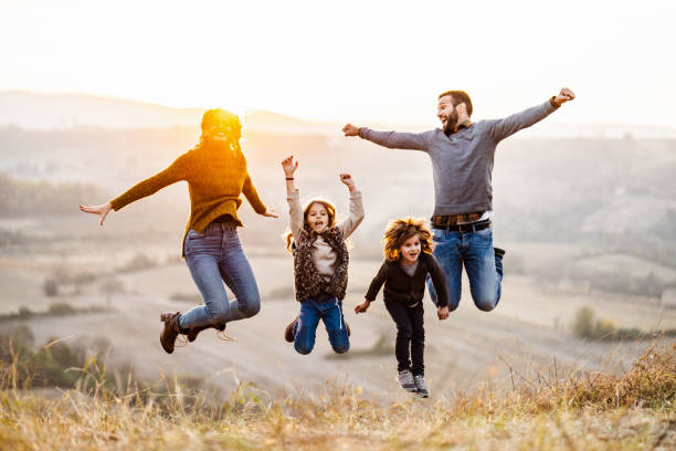istock Young happy family having fun while jumping on the field at sunset. 1080184568