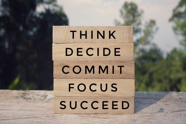‘THINK, DECIDE, COMMIT, FOCUS, SUCCEED’ written on arranged wooden blocks. Vintage styled background.