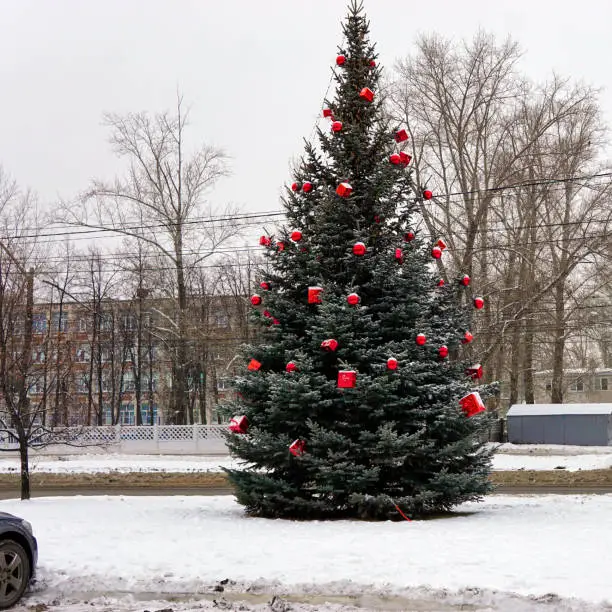 Photo of Christmas tree in the street decorated with red balls and giftboxes