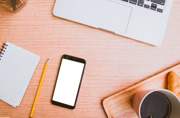 istock Mock up white screen on black mobile phone with note paper yellow pencil digital laptop and cup of coffee, croissant on wood. Filler vintage Pantone color trend for 2019 Year Top view 1080189010