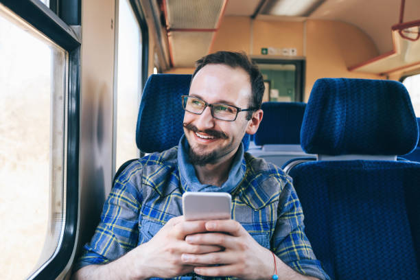 istock Smiling young man using smart phone inside of a trian 1080193848
