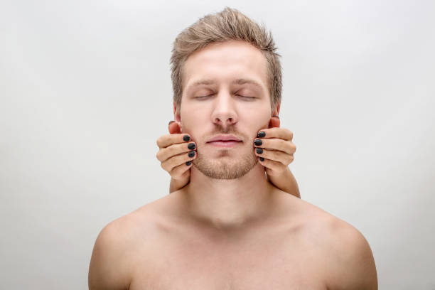 istock Young man stand with eyes closed. Woman's hands are on his cheeks. Isolated on white background. 1080199886