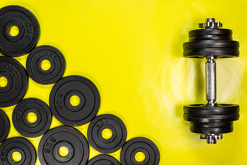 Gym dumbbells with black metal weights 1kg and 2kg on yellow background with copy sapce, Photograph taken from above.