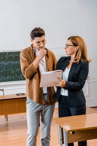 istock female teacher helping pensive male student with assignment during lesson in classroom 1080223306