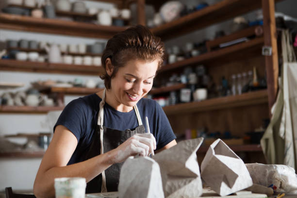 adult woman make pottery at table in workshop - earthenware imagens e fotografias de stock
