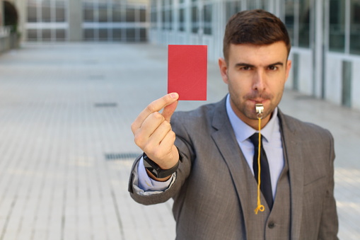 Businessman with whistle and red card.