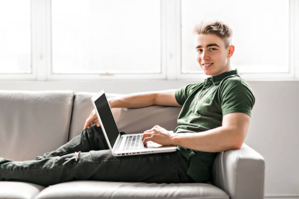 istock Handsome man using a laptop sitting on couch at home 1080228582