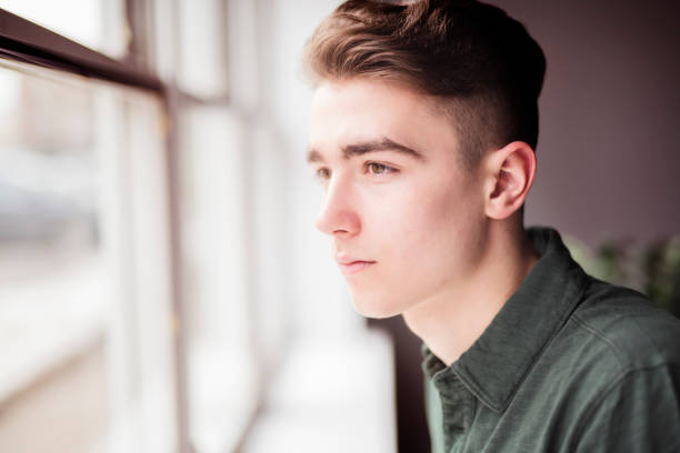 istock Man close to a window looking sad 1080230330